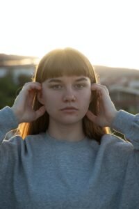 woman in gray sweater holding her face